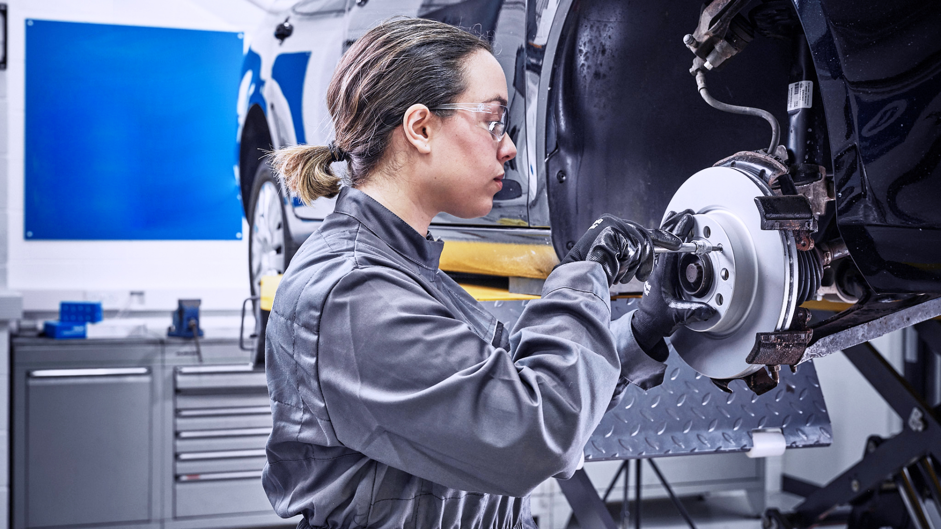 Delphi Expert replacing the front disks and brake pads of a raised vehicle.