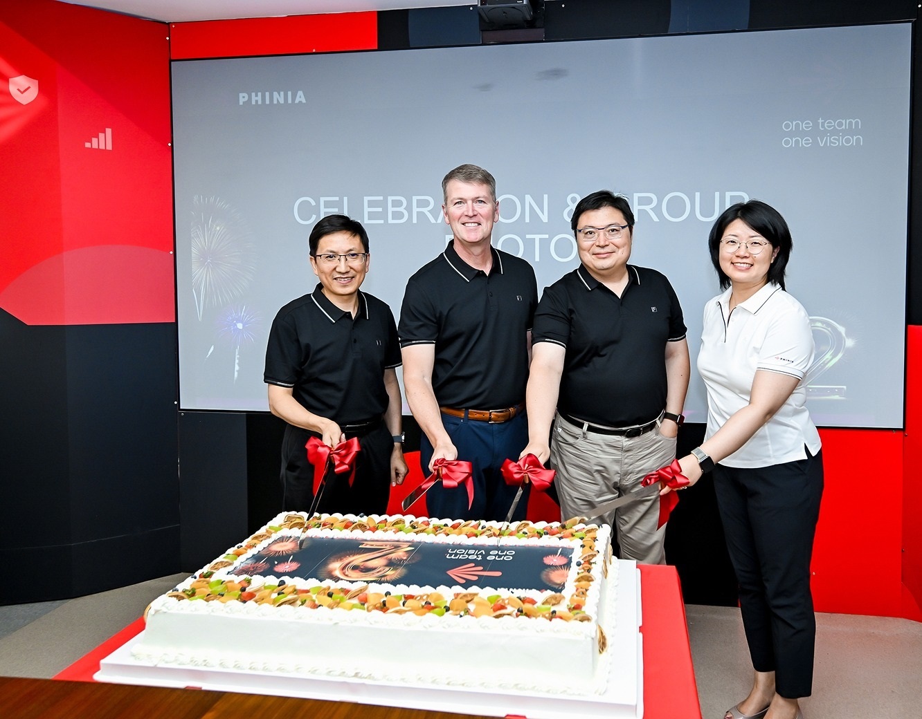 Employees cutting a cake and celebrating together at a company recognition event.