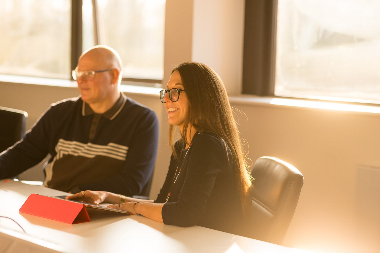 PHINIA employees participating in a meeting inside a bright, sunlit office, emphasizing teamwork and professional environment.